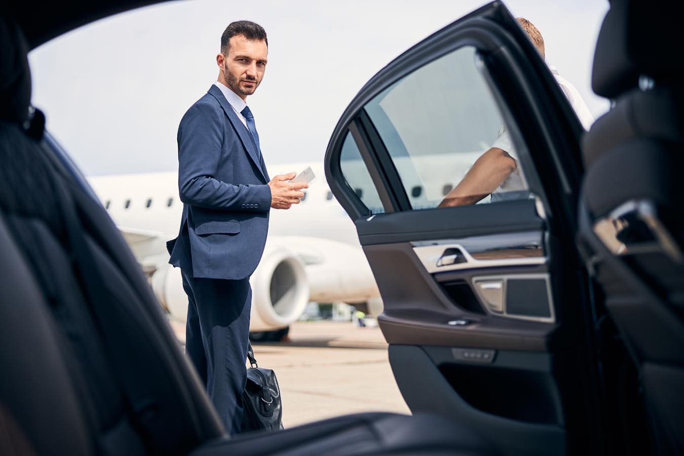 Picture of a business man standing by side of car showing aeroplane used for highlighting service of flughafentransfer Stuttgart, Waiblingen, Winnenden, Weinstadt, Fellbach, and all around Korb.